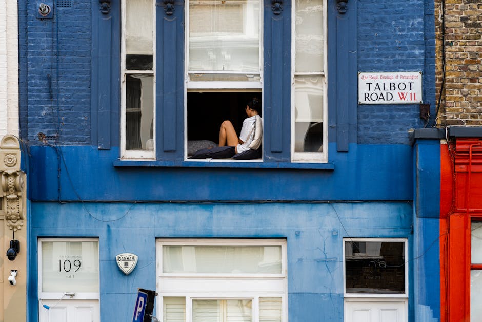 Close-up view of a white residential building with a small front porch featuring a white balustrade and a black mailbox beneath the porch. A street sign on the building's wall reads 'Portobello Road W